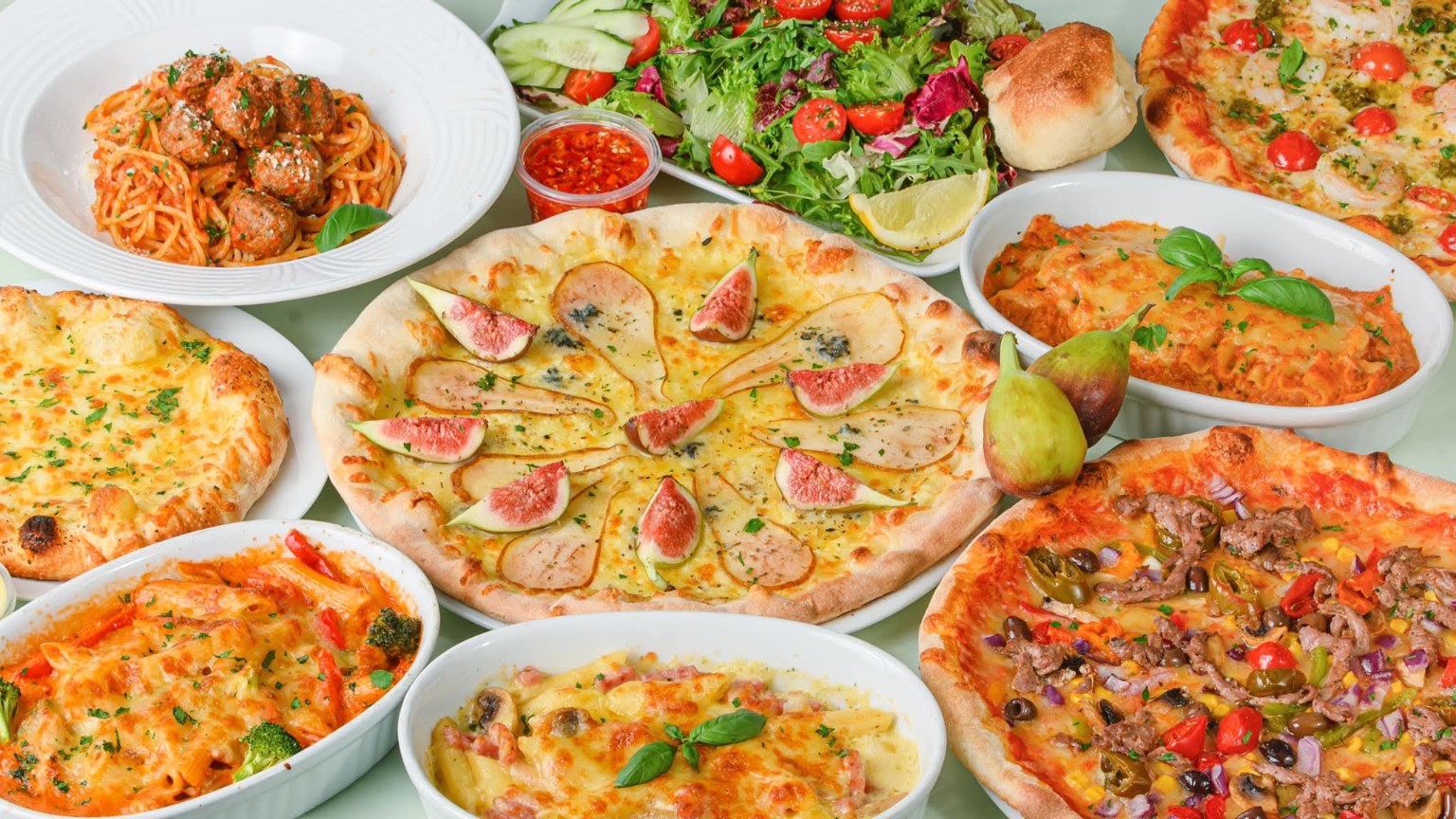 Et dekket bord med pizza, pasta og salat fra Tony’s